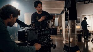 Cinematographer and camera assistant adjusting a digital cinema camera and lens on set